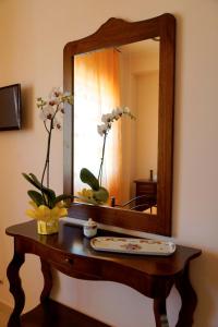 einen Holztisch mit einem Spiegel und Blumen darauf in der Unterkunft La Casa Di Mirò in Catanzaro Lido