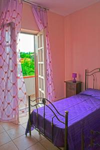 ein Schlafzimmer mit einem Bett mit violetter Bettwäsche und einem Fenster in der Unterkunft La Casa Di Mirò in Catanzaro Lido