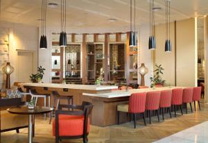 a restaurant with a bar with red chairs at Grand Mercure Medan Angkasa in Medan
