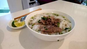 a bowl of soup with meat and noodles on a table at Rosa Hanoi Hotel in Hanoi