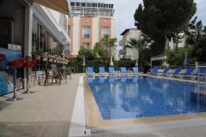 une piscine avec des chaises bleues et un bâtiment dans l'établissement Güden-Pearl, à Antalya