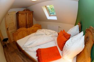 an unmade bed with orange and white pillows on it at Winzerhaus Oswald in Narrath