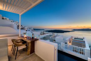 balkon ze stołem i krzesłami oraz widokiem na ocean w obiekcie Iriana Suites w Firze