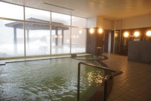 a hot tub in a room with a large window at Aguri Kobo Mabu in Otoebokke