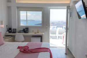 1 dormitorio con cama, escritorio y ventana en Asma Suites en Fira