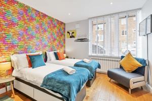 - une chambre avec 2 lits et un mur coloré dans l'établissement Rainbow Studio - By My Getaways, à Brighton et Hove