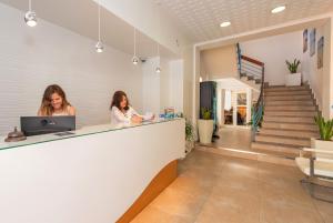 twee vrouwen aan een balie in een kantoor bij Hostal Pitiusa in Ibiza-stad