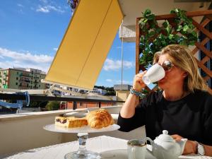 Una donna seduta a un tavolo a bere una tazza di caffè di B&B Rossini a Vieste