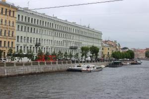 a group of boats on a river in front of buildings at Rinaldi Art in Saint Petersburg