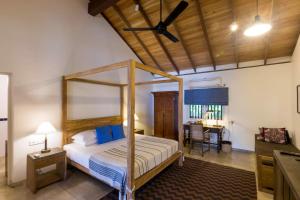 1 dormitorio con cama con dosel y escritorio en Villa Saffron Hikkaduwa en Hikkaduwa