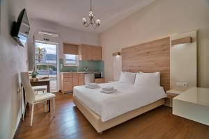 a bedroom with a large white bed and a kitchen at Emmanouela's Apts in Kissamos