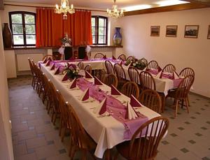 a room with long tables and chairs with pink napkins at Penzion Manský Dvůr in Dolní Žandov
