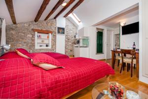 duże czerwone łóżko w pokoju ze stołem w obiekcie Studios Villa Oscar w Rovinj