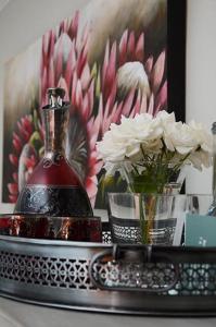 a bottle on a tray with flowers and a picture at Oleander Guest House in Kimberley