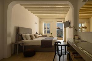 a bedroom with a bed and a desk and a window at Cova Mykonos Suites in Elia Beach