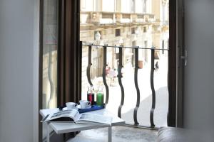 a table with books and candles and a window at Santacroce Luxury Rooms in Lecce