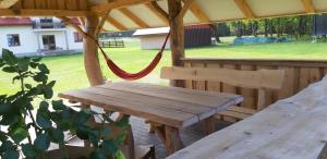 a wooden picnic table in a gazebo with a swing at Zagroda Jakubka in Myszyniec