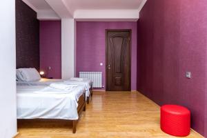 - 2 lits dans une chambre avec des murs violets et un tabouret rouge dans l'établissement Gnn Cosy Apartment, à Tbilissi