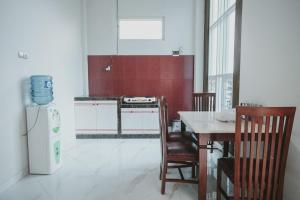 een keuken met een witte koelkast en een tafel met stoelen bij RedDoorz Syariah @ Jalan Dieng in Wonosobo