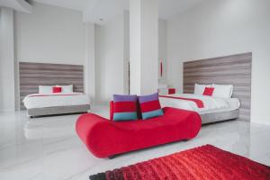 a bedroom with two beds and a red couch at RedDoorz Syariah @ Jalan Dieng in Wonosobo