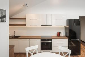 a kitchen with white cabinets and a black refrigerator at Laurentroom Park&Fountain in Ukmergė
