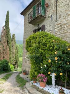 un edificio de piedra con un jardín de flores y un balcón en San Martino Vald'Afra en Sansepolcro