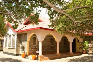 ein kleines Gebäude mit rotem Dach und Bäumen in der Unterkunft Tommy's Airport Lounge in Nairobi
