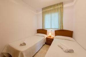 2 camas en una habitación pequeña con ventana en Playa Coral en Marina D'or, en Oropesa del Mar