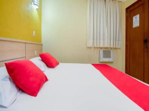 a bedroom with a large white bed with red pillows at Hotel Villa Rica in Rio de Janeiro