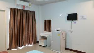 a room with a refrigerator and a tv on the wall at The Rich Home in Nakhon Ratchasima