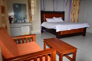 Tommy's Airport Lounge في نيروبي: غرفة نوم بسرير وكرسي وطاولة