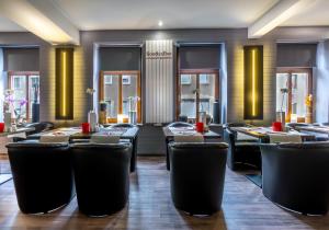 a restaurant with black chairs and tables and windows at SL'otel - Das StadtHotel - voll Klimatisiert in Bernburg