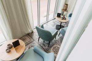 a room with blue chairs and tables and windows at Beach Hotel Helios by CW Hotel Collection in Blankenberge
