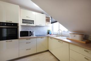 eine Küche mit weißen Schränken, einer Spüle und einer Mikrowelle in der Unterkunft Apartmani Gojević in Vodice