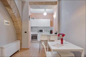 Roma Colosseum Apartment في روما: مطبخ وغرفة طعام مع طاولة وكراسي بيضاء