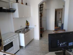 cocina con armarios blancos, fregadero y TV en casa dolce casa en Patù