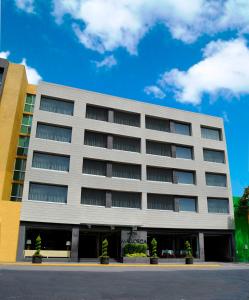 un grand bâtiment blanc avec des arbres devant dans l'établissement Mallorca Hotel , à Mexico
