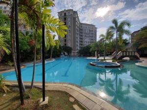 馬尼拉的住宿－Presidio lakefront 2 bedroom staycation，一座棕榈树和建筑的大型游泳池