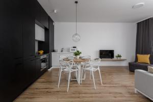 a kitchen and living room with a table and chairs at Chill Apartments Central Park in Warsaw