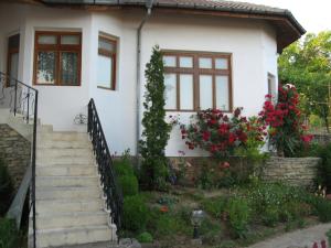 a white house with flowers in front of it at Guest House Astra in Arbanasi