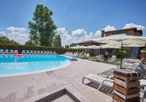 einen Pool mit Stühlen und einem Sonnenschirm in der Unterkunft Villaggio Turistico Lugana Marina in Sirmione