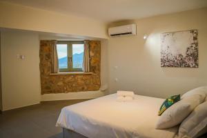 1 dormitorio con cama blanca y ventana en GAGOUINOS COTTAGE, en Koríthion