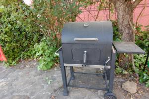 a grill sitting next to a table next to a tree at Apartamento El Fenal de Turmo Casa rural "El Capricho de Nieves" in Laspuña