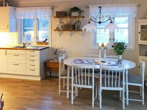 eine Küche mit einem weißen Tisch, Stühlen und Fenstern in der Unterkunft 6 person holiday home in Ballangen in Ballangen