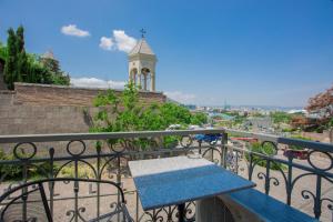 un banco azul en un balcón con una torre de reloj en GTM Kapan, en Tiflis