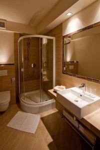 La salle de bains est pourvue d'une douche, d'un lavabo et d'un miroir. dans l'établissement Hotel Tumski, à Płock