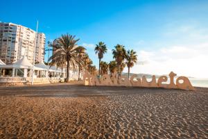 a sign on a beach with palm trees and the ocean at Novotel Suites Malaga Centro in Málaga