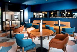 un restaurante con paredes azules, mesas y sillas en Hotel Le Bugatti, en Molsheim