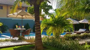 a patio with a table and chairs next to a pool at Ravenala Hotel Boutique in Canoa Quebrada