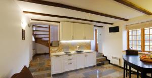 a kitchen with white cabinets and a sink and a table at Alėjos Namelis in Palanga